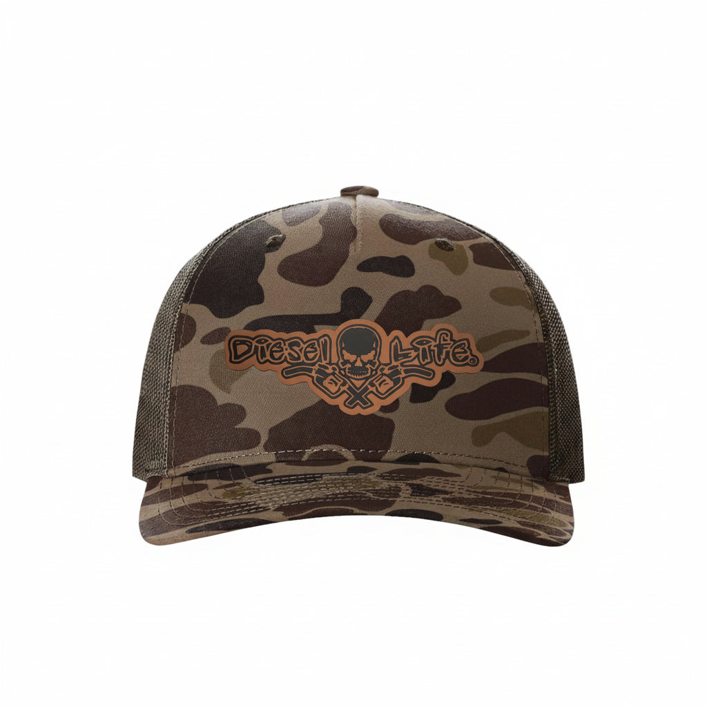 A camouflage trucker hat with brown mesh back panels and a prominent embroidered 'Diesel Life' skull and crossed guns logo on the front.